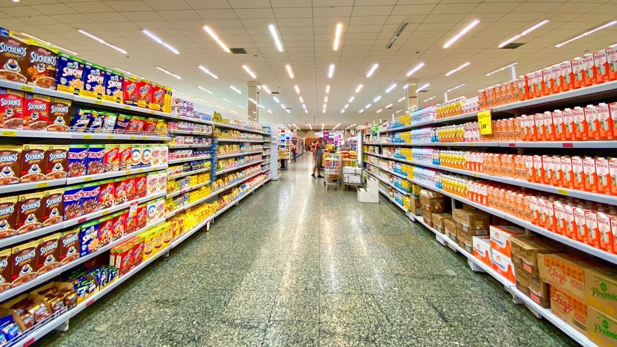 Consumidor comparando produtos semelhantes em prateleira de supermercado