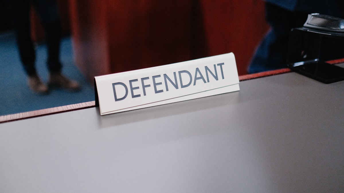 Público atento em tribunal durante julgamento penal com defesa atuante