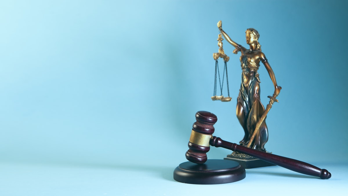 Balança da justiça ao lado de contrato com caneta sobre mesa