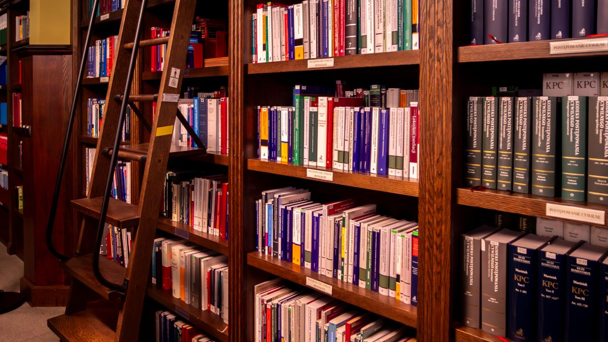 Livros jurídicos alinhados em estante de biblioteca especializada