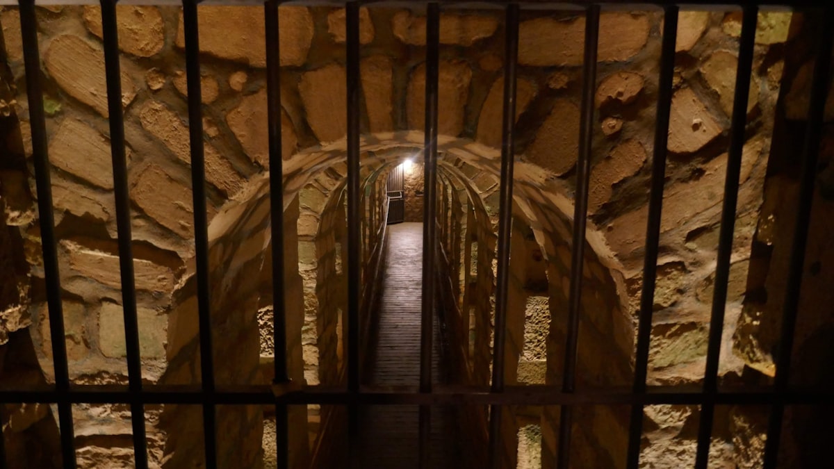 Corredor de presídio com portas fechadas e iluminação baixa