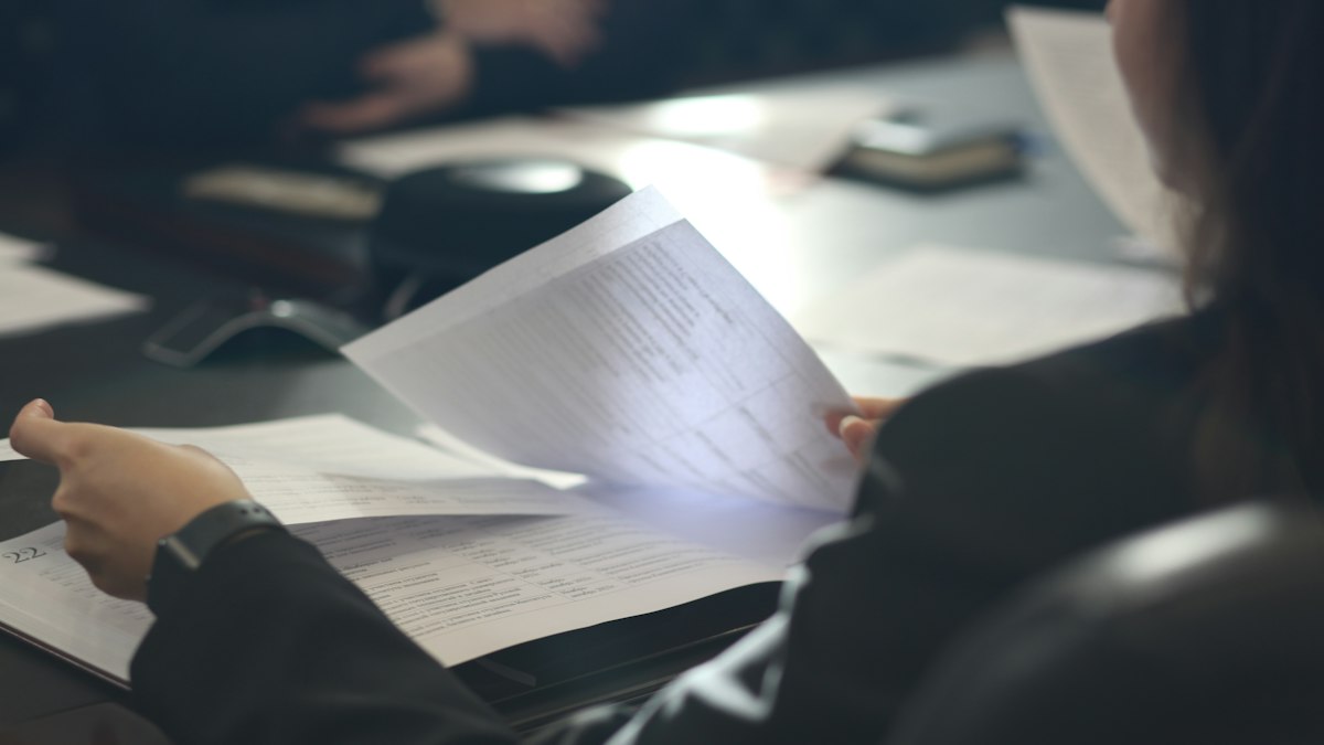 Documentos de prova material analisados com lupa em mesa de escritório
