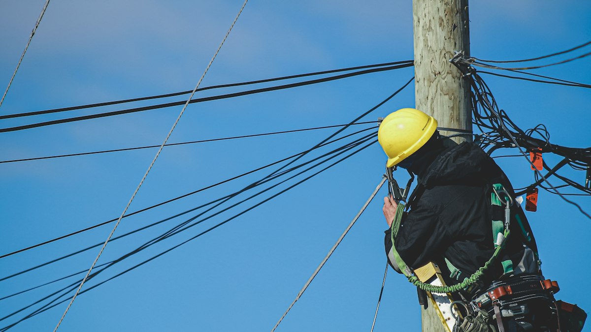 Equipe técnica em poste verificando medidor de energia elétrica urbana
