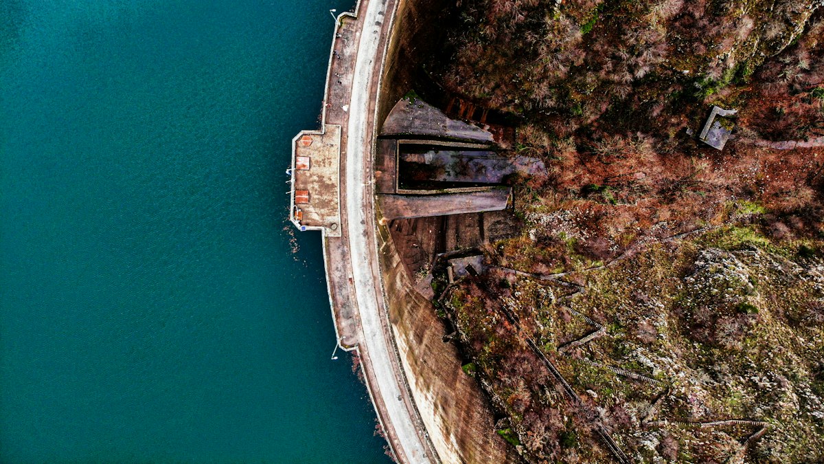 Vista aérea de barragem hidrelétrica e reservatório em região montanhosa