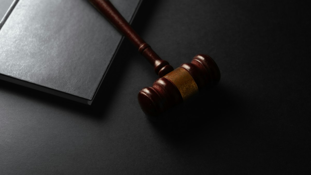 Martelo de juiz sobre mesa de tribunal com documentos ao fundo
