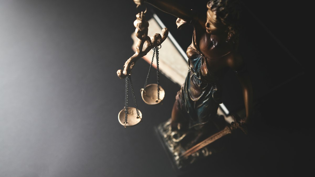 Balança da justiça sobre mesa com códigos e documentos