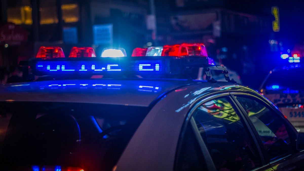 Viatura policial em patrulhamento noturno em avenida movimentada